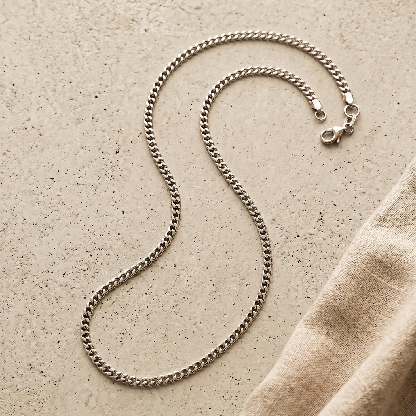 Cuban Link Kette Silber, Stillleben auf hellem Beton mit Leinen