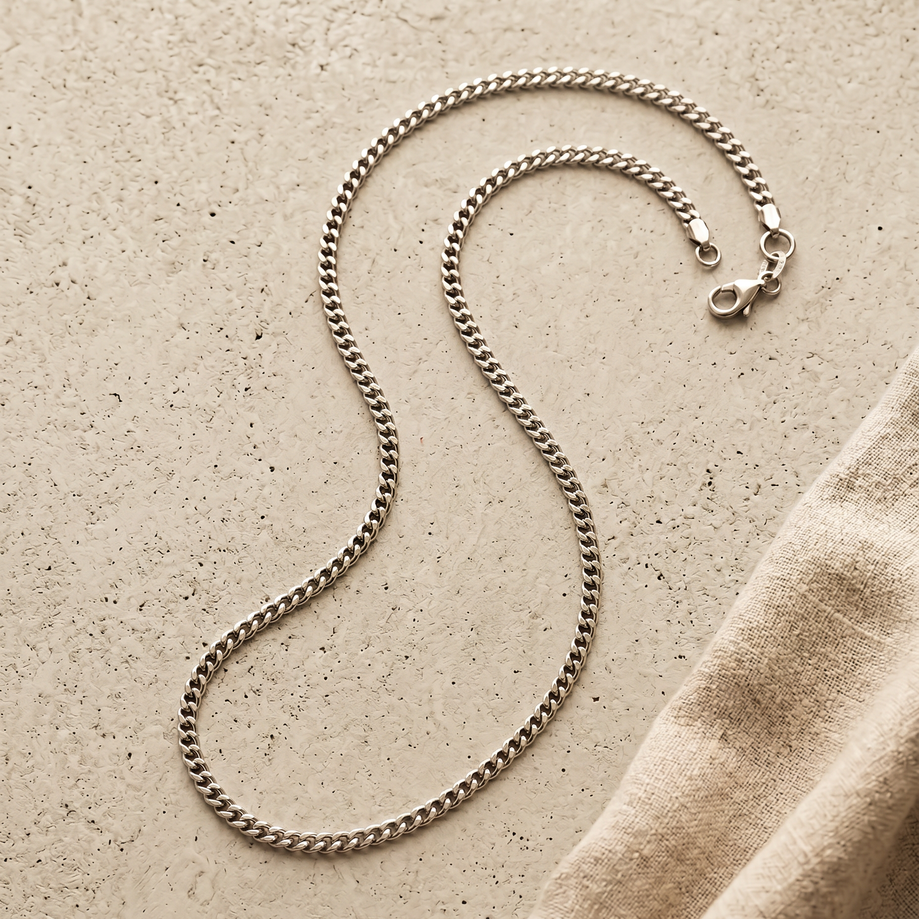 Cuban Link Kette Silber, Stillleben auf hellem Beton mit Leinen