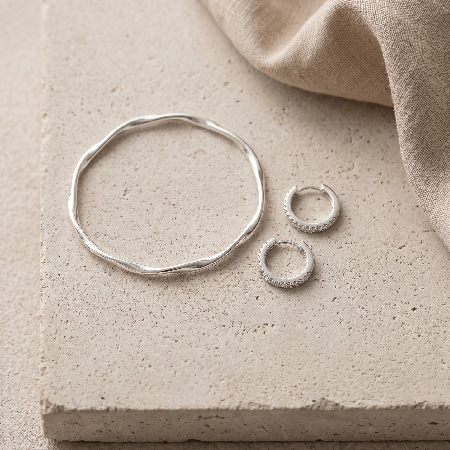 Silver Statement Set Flatlay: silberner Twist Armreif und Pavé Creolen