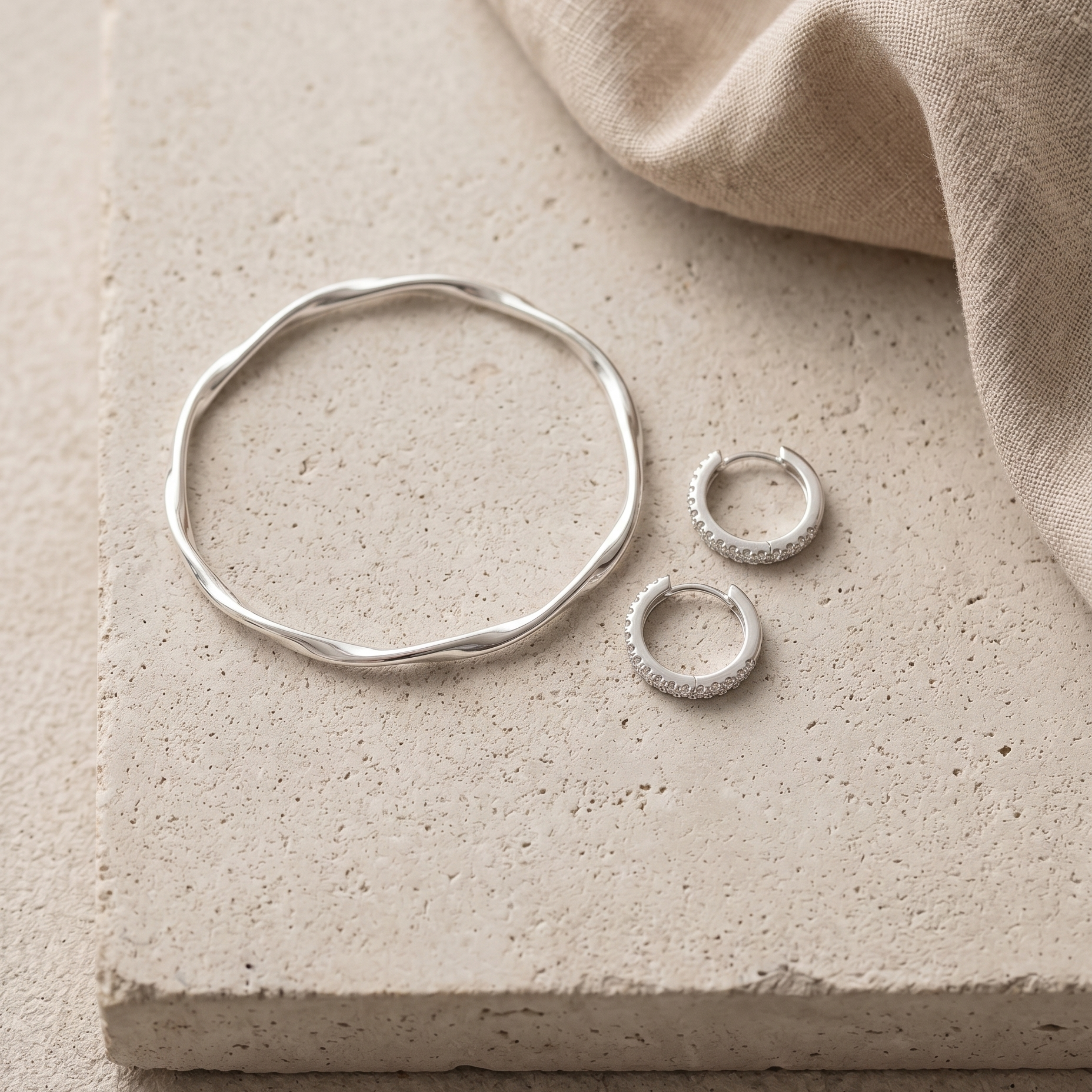 Silver Statement Set Flatlay: silberner Twist Armreif und Pavé Creolen